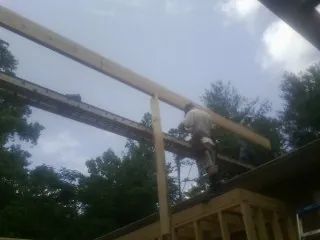 Carpenter setting a ridge beam over a new addition frame — Ice Dam Removal by Roofing Brothers in Mcclellan