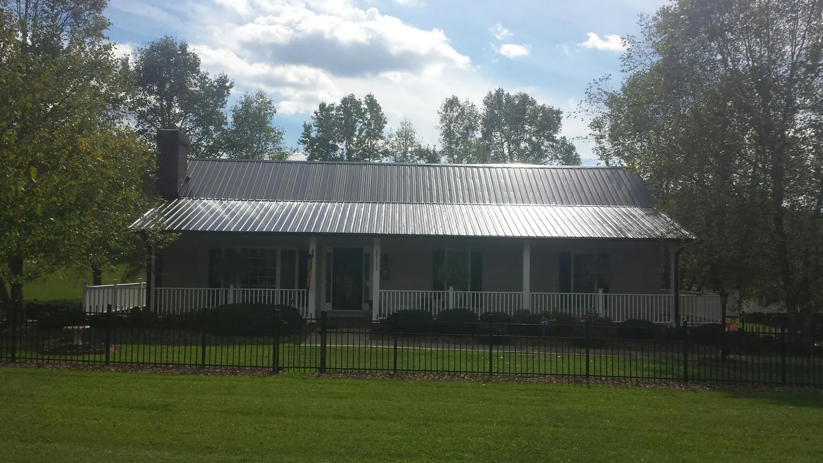 Gray metal roof on a brick ranch with a full width front porch — Gutter Guard Installation work by our crew in Mcclellan